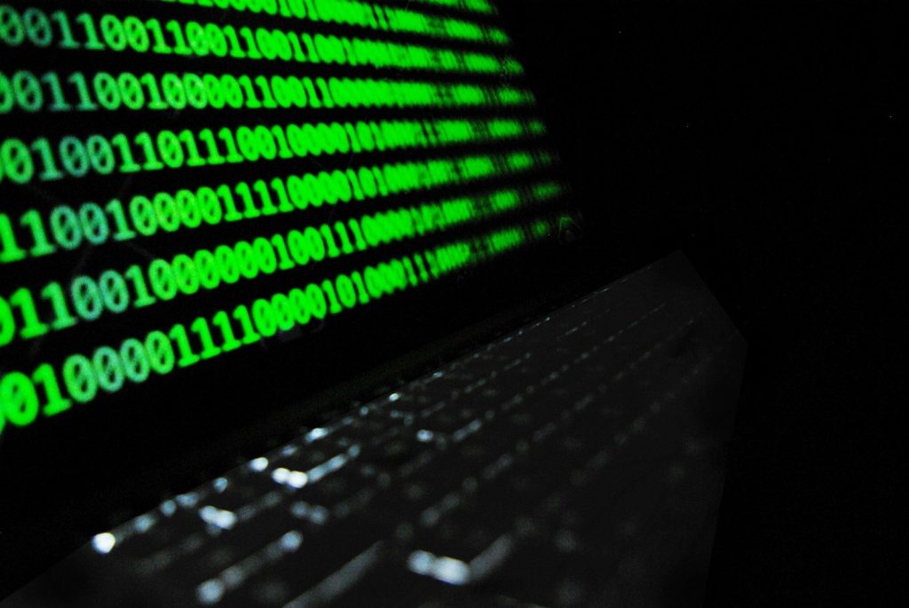 Tamsus laptop'as su šviečiančiu programos kodu — zero-day spragos vizualizacija